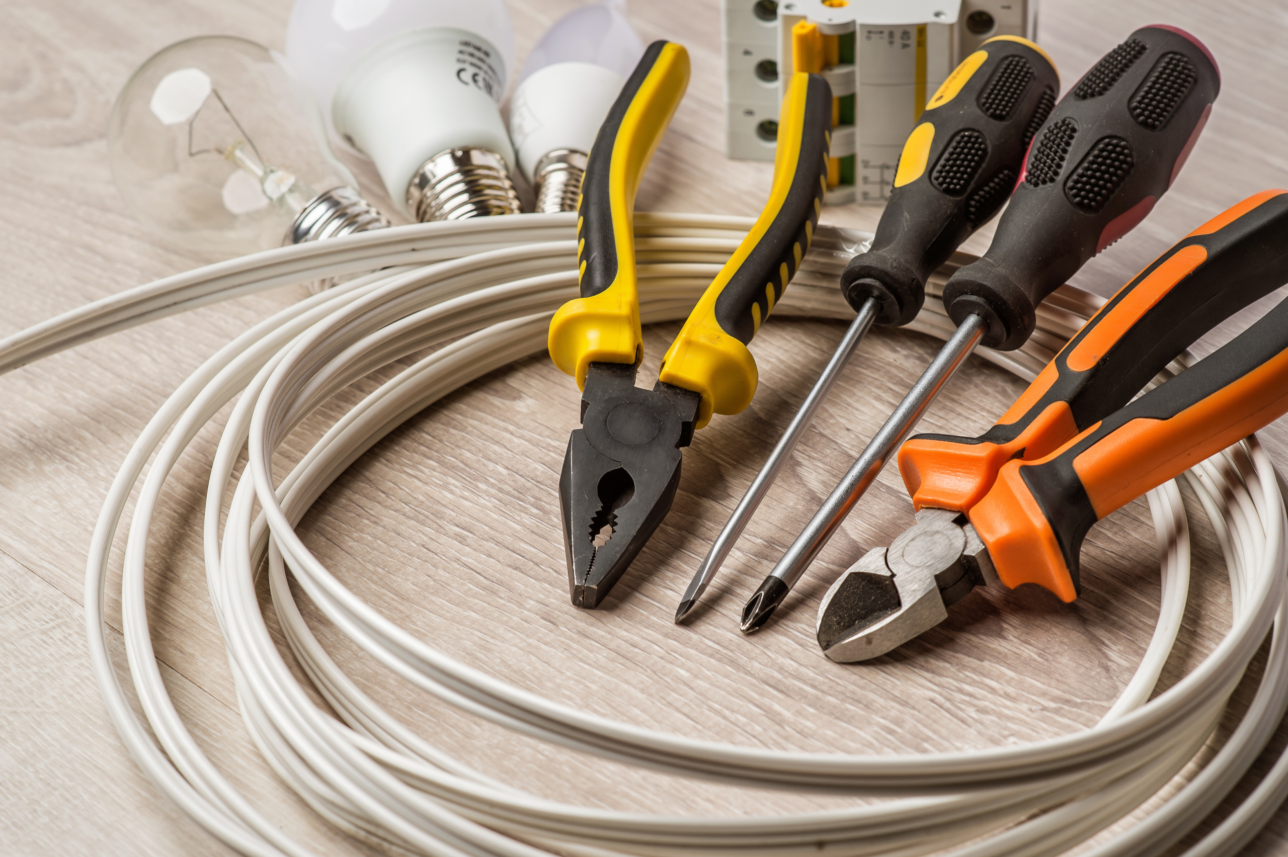 set of electrician tools, a coil of wire and equipment in backgr -  Electrical Installations